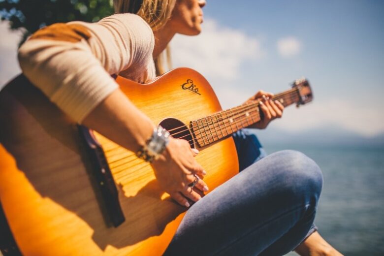 blonde-woman-playing-guitar-at-seaside